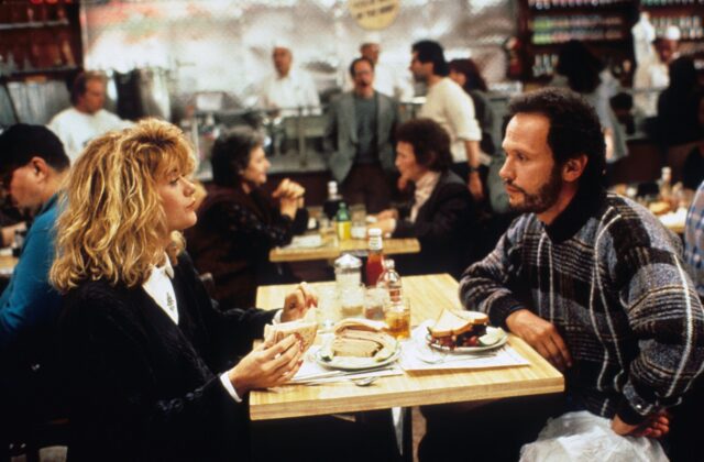 Meg Ryan sitting across a table from Billy Crystal in a busy diner, a scene from "When Harry Met Sally."