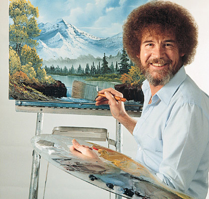 A photo of Bob Ross in front of a painting holding a palette and paintbrush.