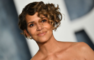 Halle Berry with short hair in a strapless dress smiling for the camera.
