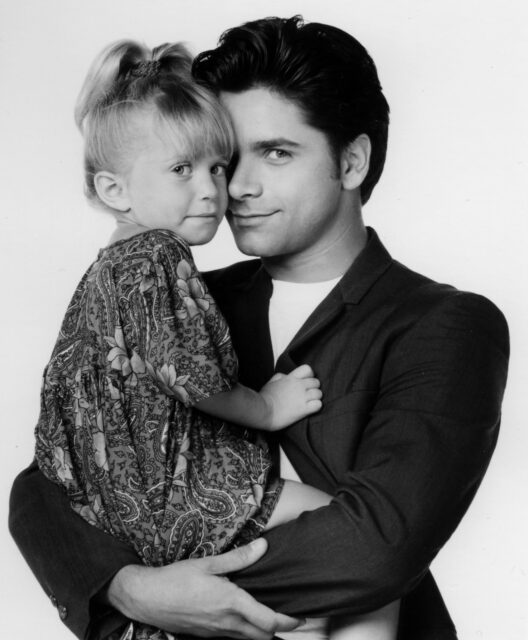 John Stamos holding one of the Olsen twins in his arms
