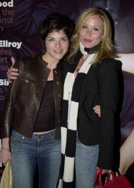 Christina Applegate and Selma Blair side-hugging and smiling.