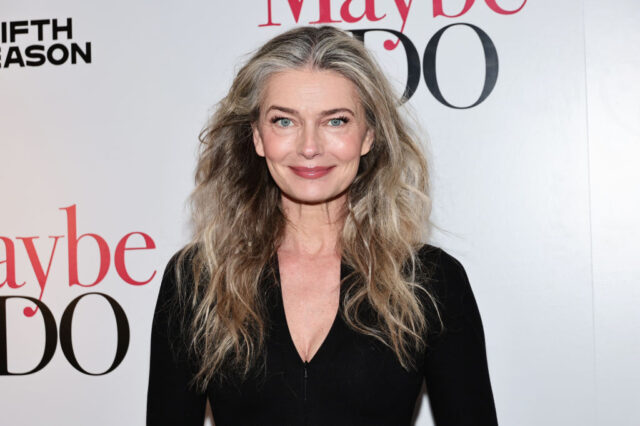 Paulina Porizkova in a black long sleeve shirt posing in front of a backdrop.