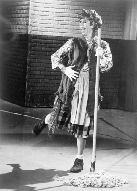 Carol Burnett dressed as a char-woman dancing on her television show. 