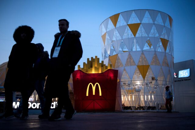 People walk past a McDonalds outlet in the Gangneung Olympic Village in Gangneung on February 8, 2018, ahead of the Pyeongchang 2018 Winter Olympic Games. 