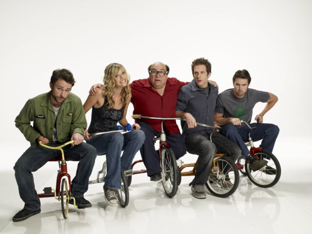Charlie Day, Kaitlin Olson, Danny DeVito, Glenn Howerton, and Rob McElhenney sit on tricycles 