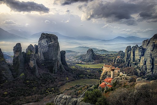 Aerial view looking down at the large rock formations and Monastery of Meteora Valley.