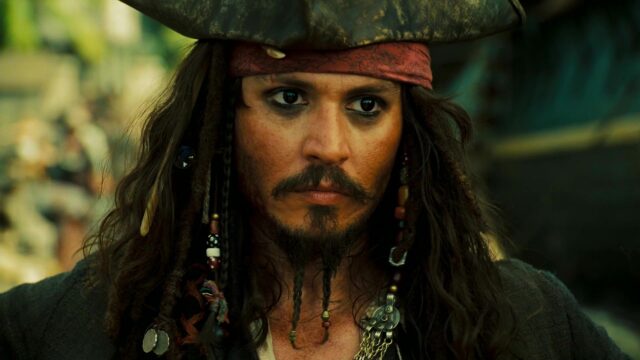Portrait of Johnny Depp as Jack Sparrow, in a pirate hat with braids in his hair and beard. 