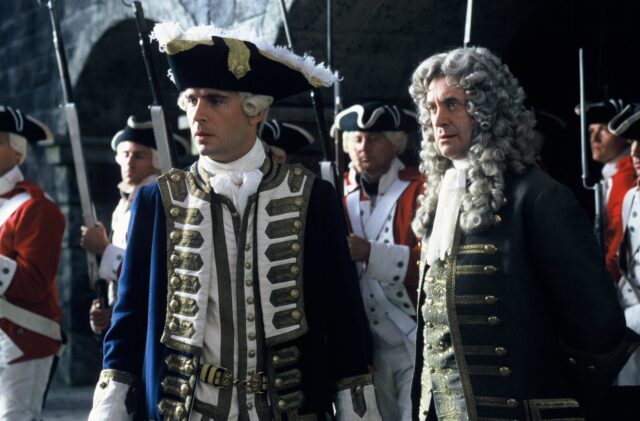 Group of actors dressed as British Navy officers in powdered wigs and elaborate jackets.