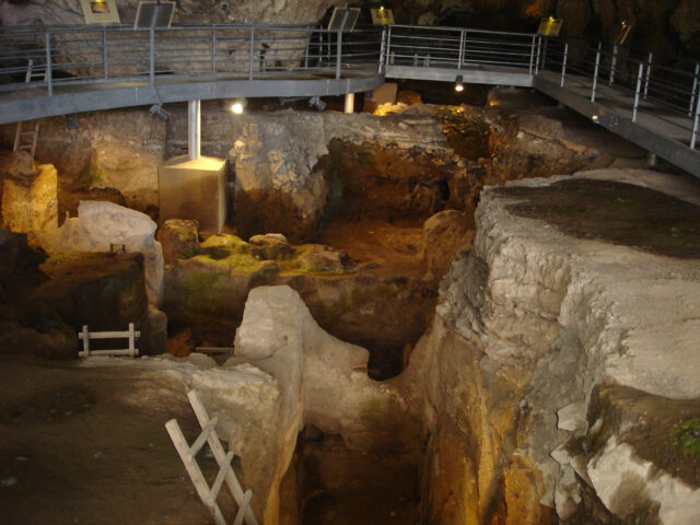 Excavation of a rocky pit surrounded by a metal walkway.