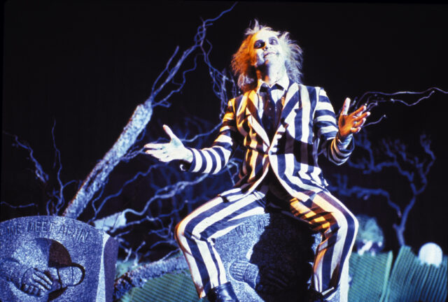 Michael Keaton sitting on a gravestone as Beetlejuice