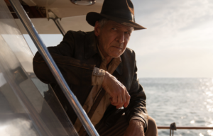 Harrison Ford as Indiana Jones, leaning against a wall on a boat.