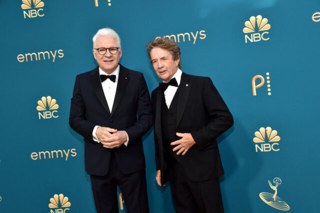 Steve Martin and Martin Short posing on the red carpet in matching black formal suits. 