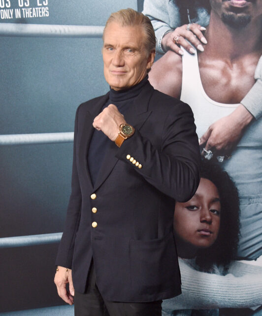 Dolph Lundgren holding his hand up in front of his chest in a fist.