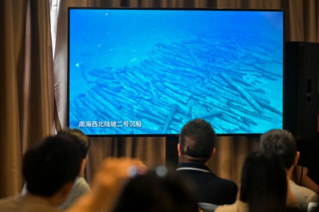 View of a screen showing numerous wooden poles stacked together underwater.