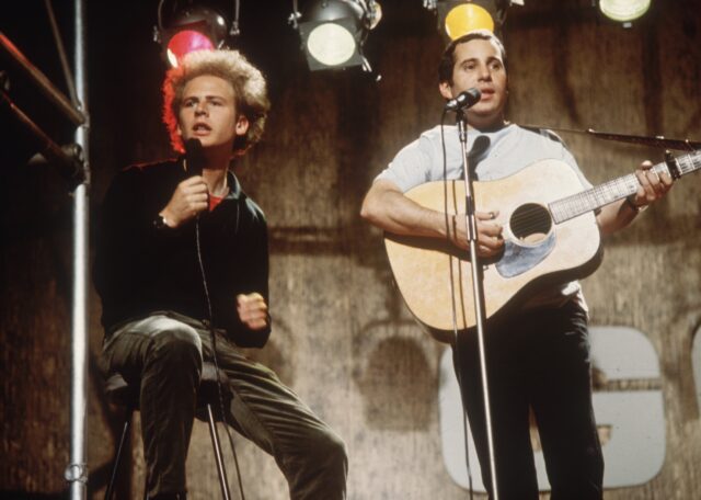 Art Garfunkel and Paul Simon singing on stage.