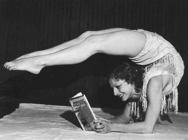 Gertrude Fisher reading a book while in a contorted pose