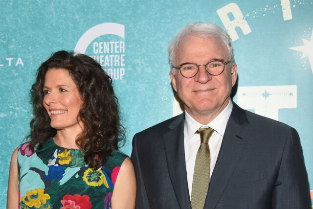 Steve Martin and Edie Brickell pose in front of a turquoise backdrop. 