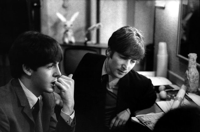Paul McCartney sitting with John Lennon