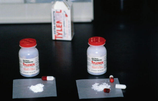 Two bottles of extra-strength Tylenol with split capsules placed in front of them