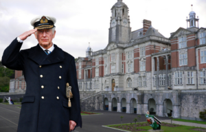 Prince Charles salutes at Britannia Royal Naval College in December 2021. Background, Britannia Royal Naval College and the college's parade ground