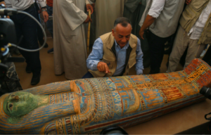 Man crouching beside an ancient Egyptian sarcophagus