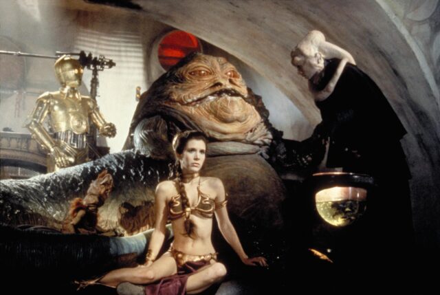 A scene from 'Return of the Jedi,' with Carrie Fisher as Leia sitting in front of Jabba the Hutt