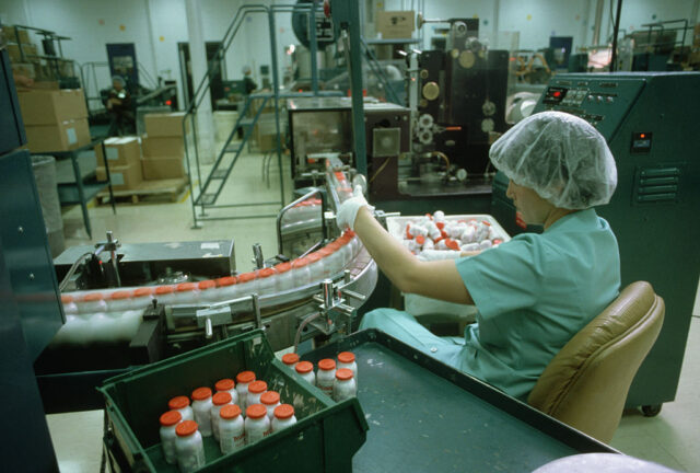 Female worker examining bottles of Tylenol along a production line
