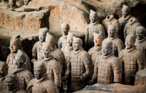 Several terracotta warriors stand in line with eachother.