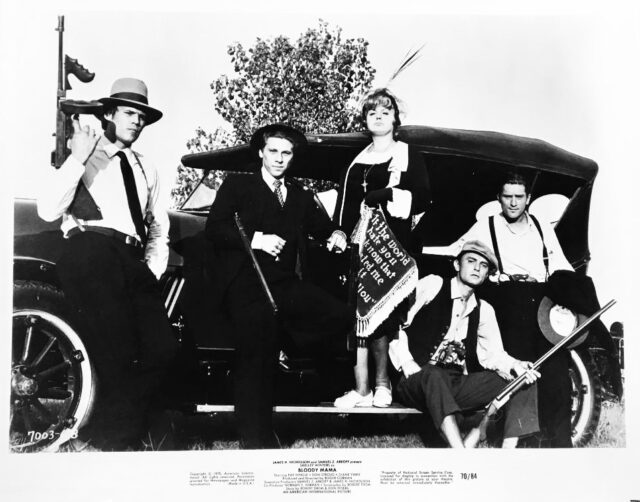 Shelley Winters as Ma Barker, Robert Walden as Fred Barker, Don Stroud as Herman Barker, Clint Kimbrough as Arthur Barker, and Robert De Niro as Lloyd Barker pose with a car and guns for a movie still.