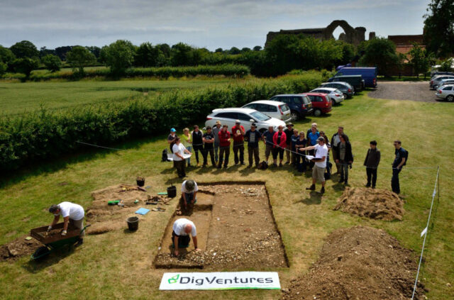 People gathered near a church, digging up an area.