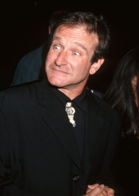 Robin Williams standing with his eyes opened very wide