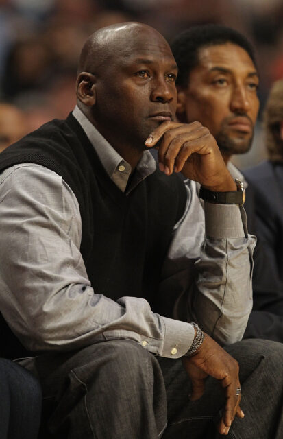 Michael Jordan sitting beside Scottie Pippen, his hand to his chin.