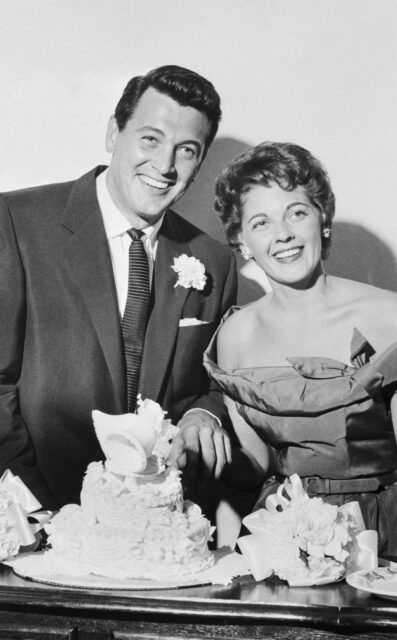 Rock Hudson and Phyllis Gates pose cutting the cake at their wedding.