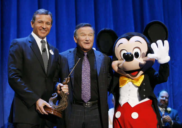 Robin Williams standing on-stage with Bob Iger and Mickey Mouse
