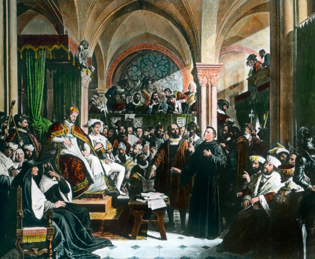 A painting of Martin Luther speaking to a hall of nobility.