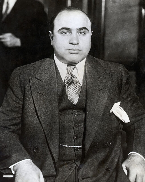 Photo of Al Capone wearing a three piece suit and sitting in a chair