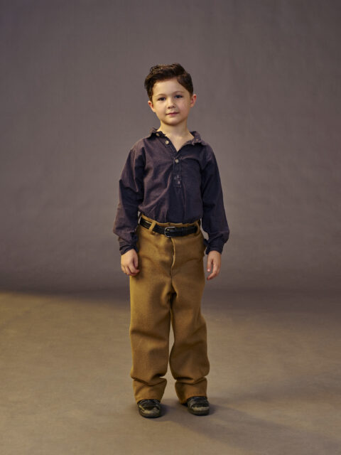 Blane Crockarell as Bobby Parton in a blue shirt and brown pants. 