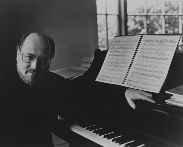 John Williams posed for a photo at a piano.