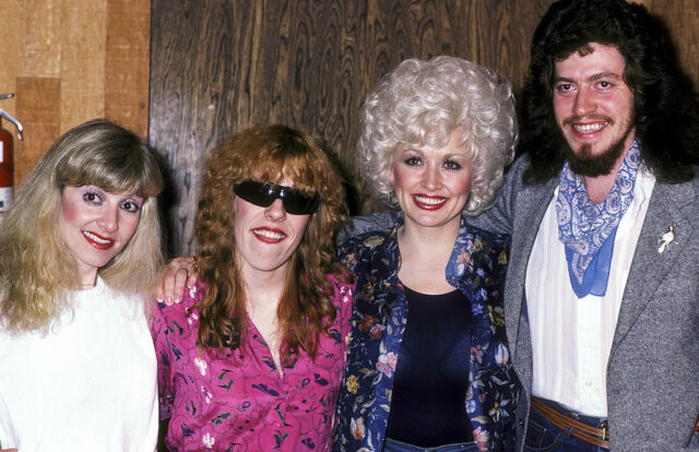 Stella Parton in a white shirt, Freida Parton in a pink floral shirt and sunglasses, Dolly Parton in a blue floral shirt, and Floyd Parton in a white shirt, grey jacket, and blue neck scarf. 