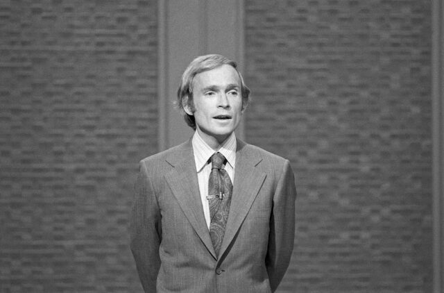 Dick Cavett in a suit and tie on set of his talk show.