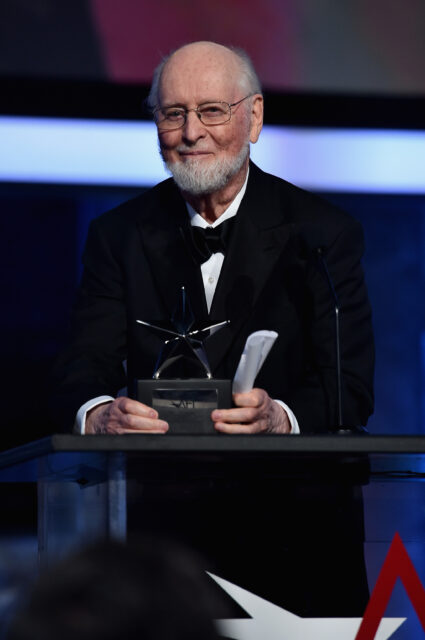 An older John Williams accepting an award at a podium.