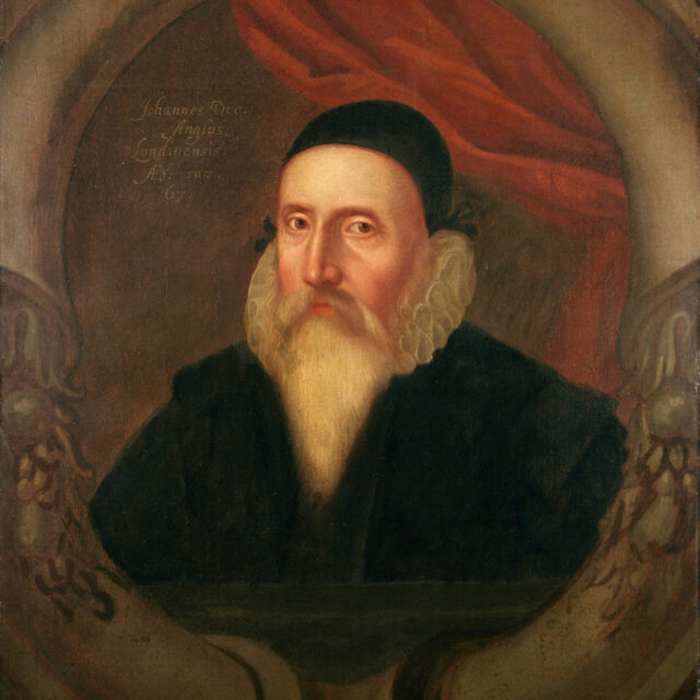 Portrait of John Dee in a black robe, black cap, and with a long white beard. 