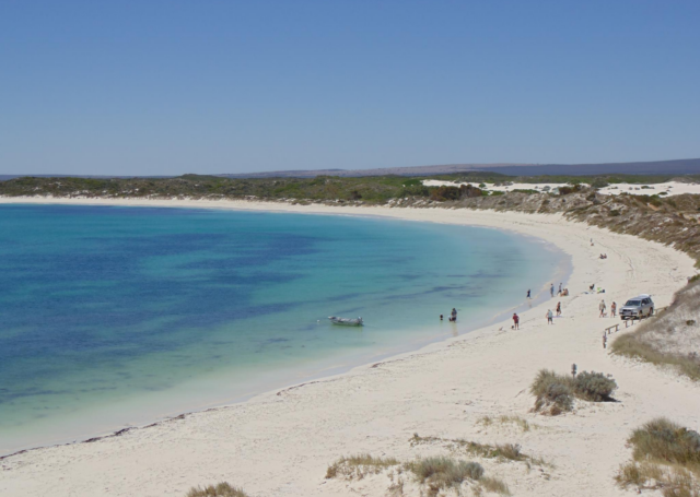 Aerial view of a beach with people walking on it.