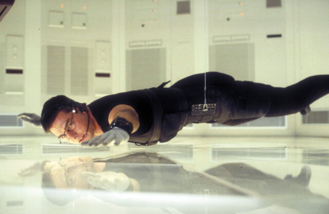 Tom Cruise hanging from the ceiling over the ground in a scene from 'Mission: Impossible'