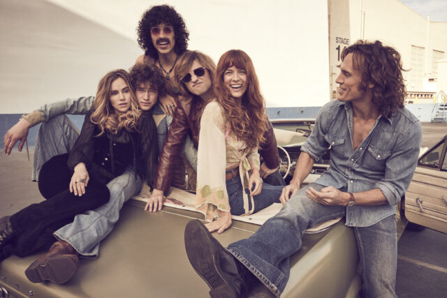 Cast of 'Daisy Jones & The Six' sitting on the trunk of a car