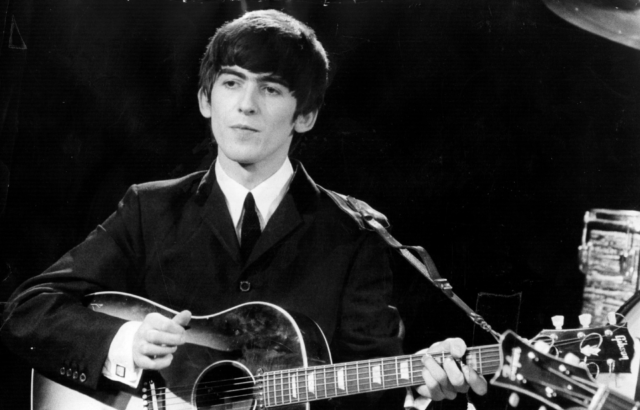 George Harrison playing the guitar on stage