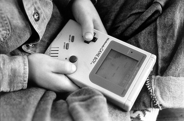 Young kid playing on a gameboy.