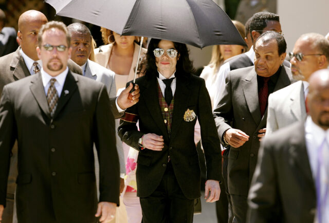 Michael and Joe Jackson walking among a large crowd of people