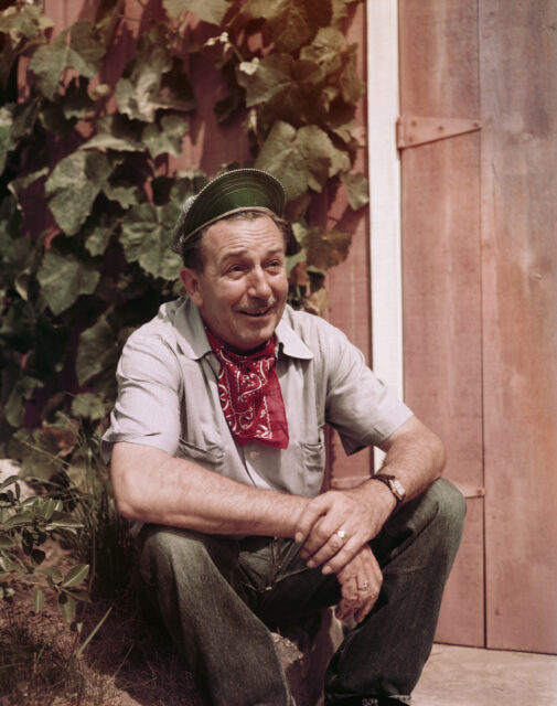 Walt Disney sitting, wearing a hat and bandana