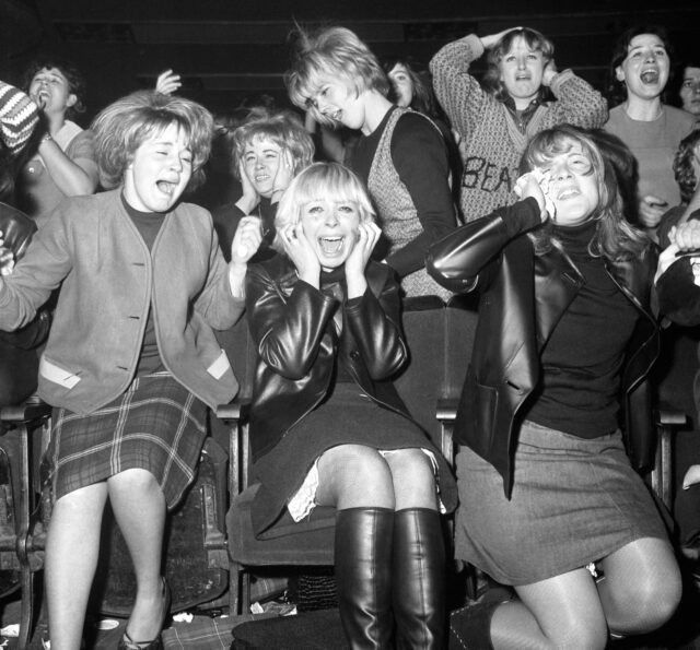 Girls screaming, losing their composure at a Beatles concert.